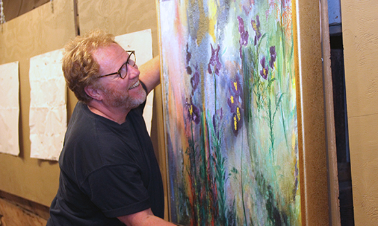 Michael Lewis hangs art in preparation of the opening of the Big Red Barn art show. Photo: Rebecca Silbernagel/VAF
