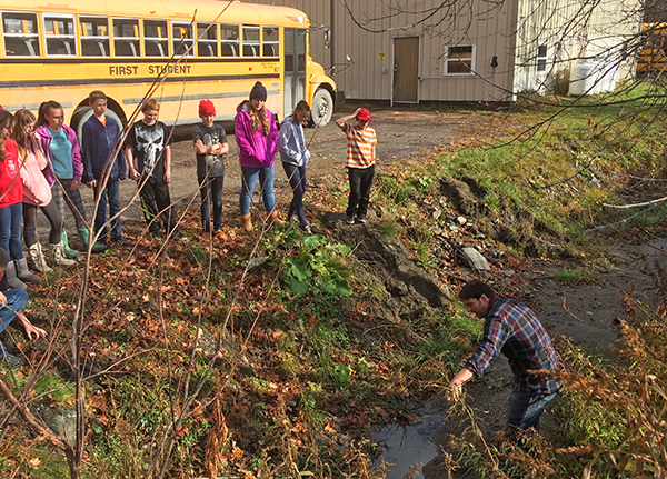 Harwood seventh-graders investigate stormwater catch basin to trace the path of water running off their classroom’s roof. Photo: Friends of the Mad River