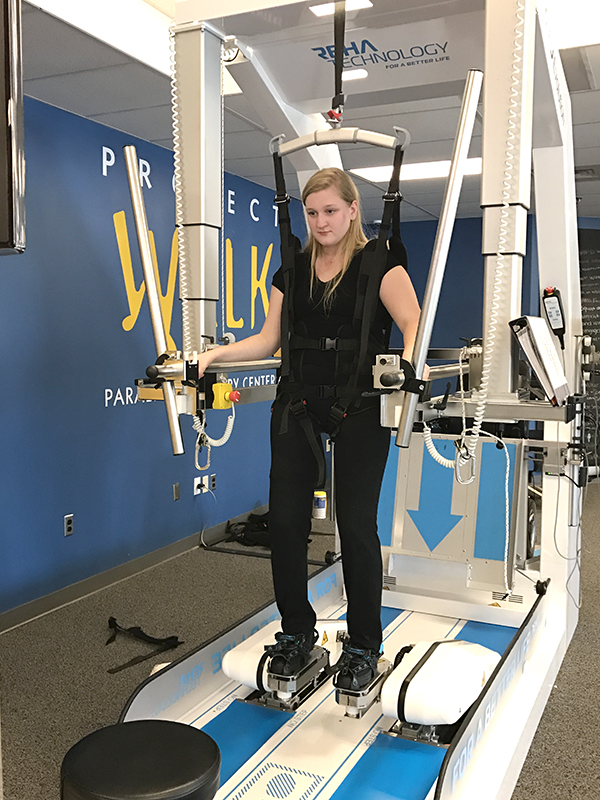 Lily Stilwell, Fayston, uses an assisted walking machine as part of her ongoing therapy following a spinal injury in October. Friends are raising funds to modify her home.
