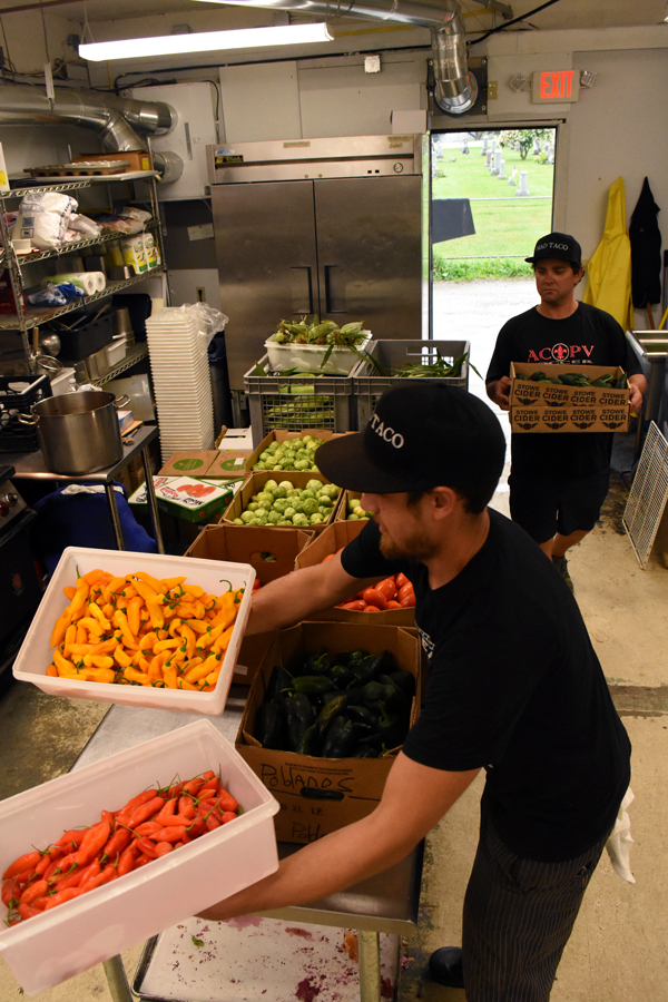 Kit Perreault and Josh Wedel carry in boxes of produce that was grown at The Mad Taco’s farm on Marble Hill Road. Photo: Christopher Keating