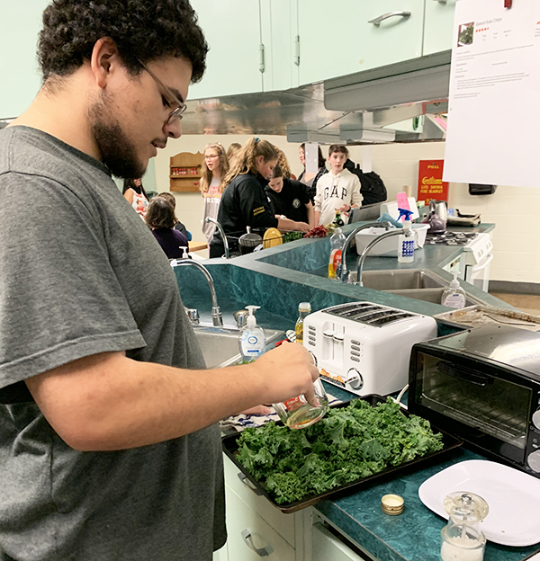 Senior Daniel Robinson prepares a kale dish for the fall harvest lunch at Harwood.