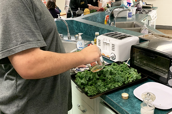 Senior Daniel Robinson prepares a kale dish for the fall harvest lunch at Harwood.