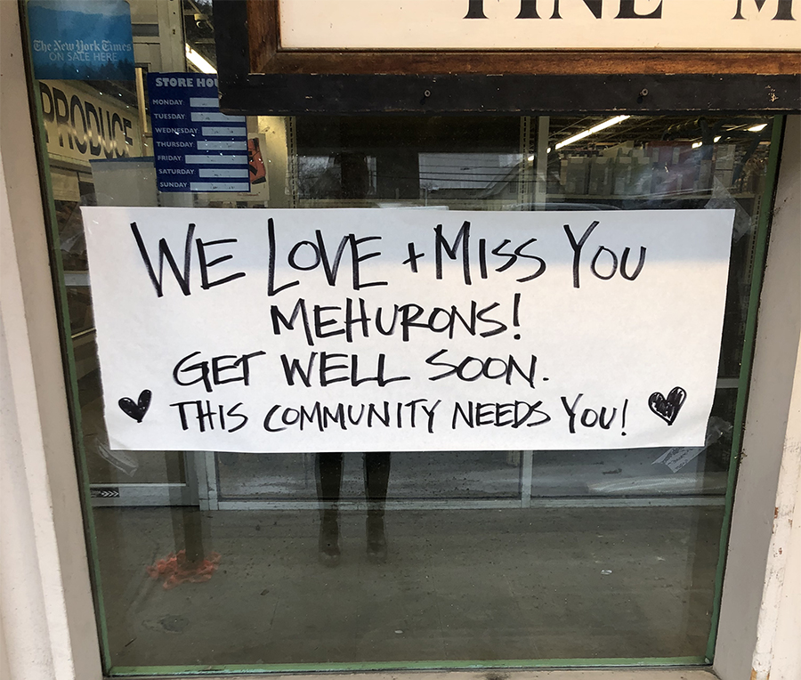 Sign showing community support stuck to window of Mehuron's Supermarket after smoke damage from an adjacent fire.