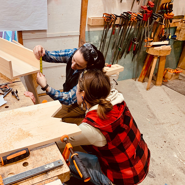 Instructor Lindley Brainard checks a measurement with one of her students in the Powertools for Women course recently held at Yestermorrow. Photo: Hadley Laskowski. 