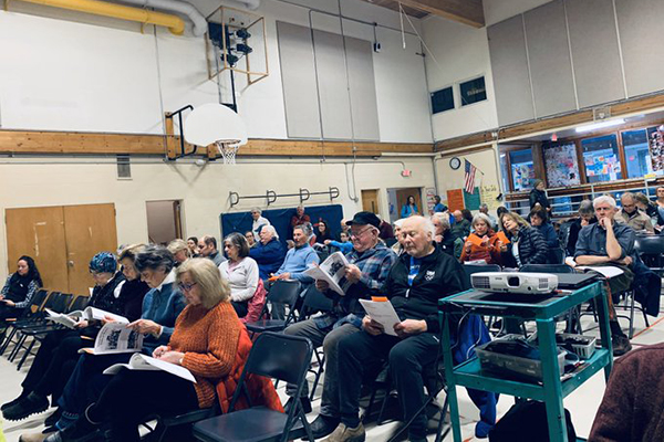 Warren residents study their town reports as they await the beginning of Town Meeting. Photo: Hadley Laskowski.i