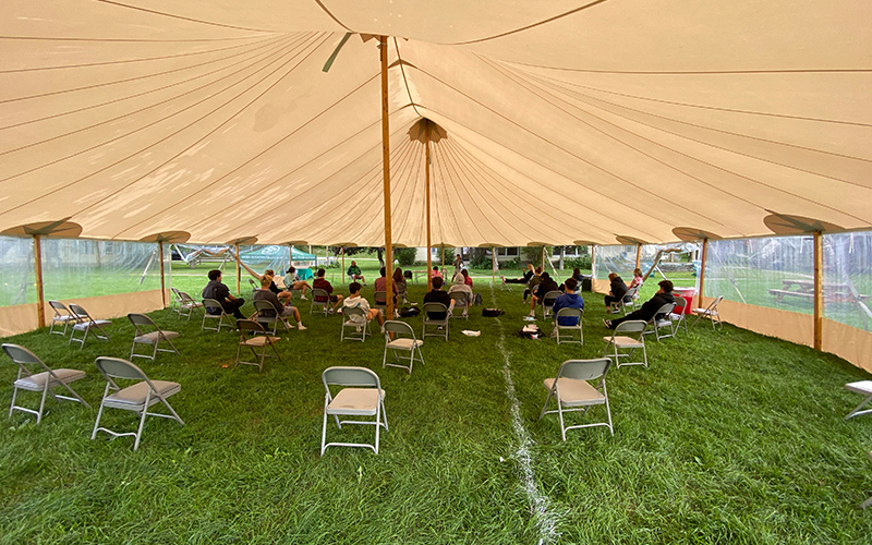 Students engage in orientation under the tent.