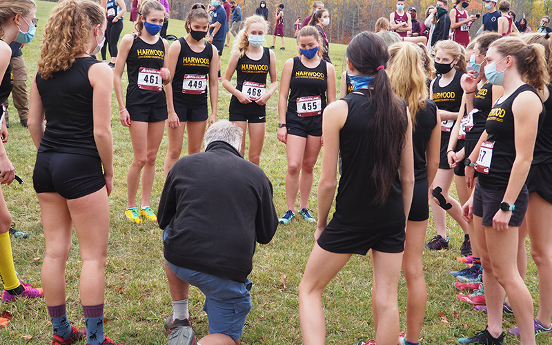 Harwood Cross Country Coach John Kerrigan kneels and talks strategy with the girls team before a race. Photo: Ann Zetterstrom 