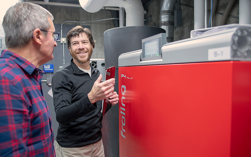 Dave Frank, Fayston, cofounder of SunWood Biomass, shows Mané Alves, founder of Vermont Artisan Coffee & Tea, the workings of a wood pellet boiler system installed at the coffee company’s Route 100 facility in Waterbury Center. 