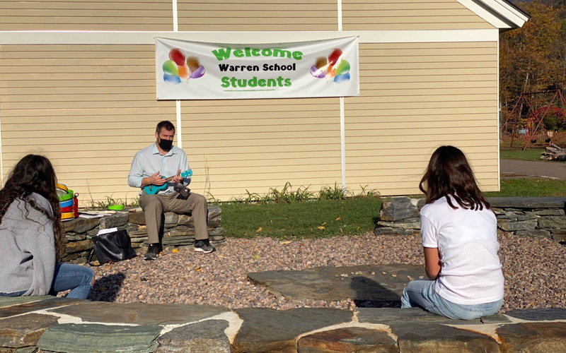 Music teacher Jeremy Hill conducts and outside lesson at Warren Elementary School.