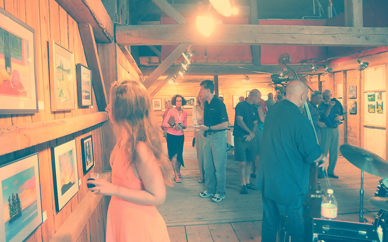 People looking at art on the walls of the Big Red Barn while a jazz band plays.