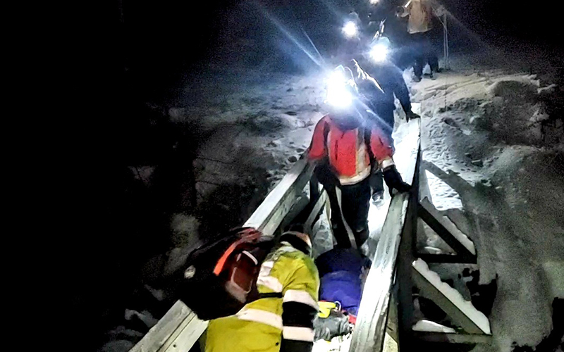 Rescue personnel transport the injured skier out of the woods by sled.