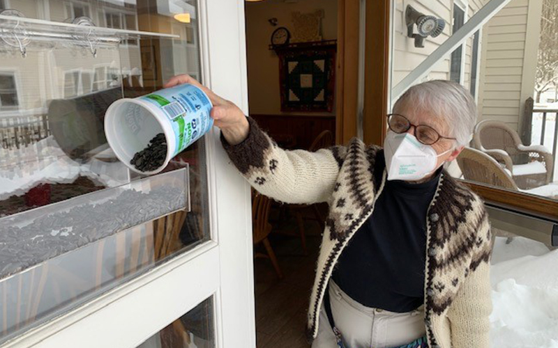 Pat Folsom loading up one of the bird feeders at Evergreen Senior Center. Photo: Nancy Emory.