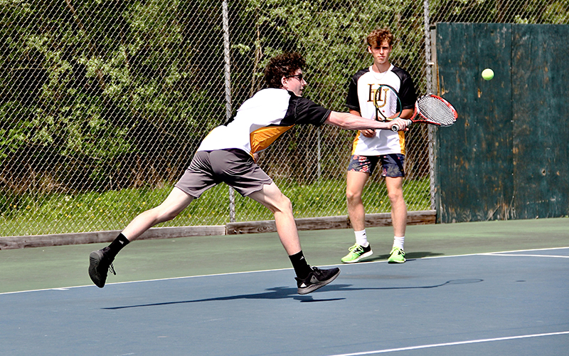 Colin Deschamps (left) runs crosscourt to return a ball during the team warm-up.  Xavier Brookens (right) prepares to provide backup for his doubles teammate. Photo: Roarke Sharlow.