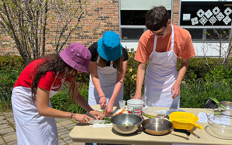 Three Harwood seniors cutting vegetables as part of the Junior Iron Chef competition.