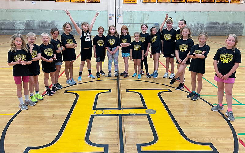 Harwood girls' basketball camp gather at the center circle for a photo.