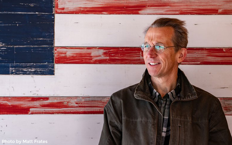 Charlie Kimbell standing in front of an American flag painting.