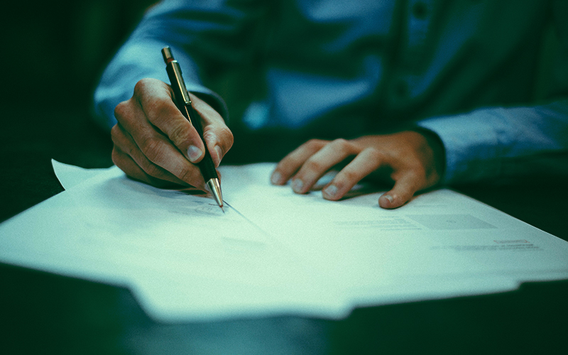 Closeup of hand writing letters at a desk.