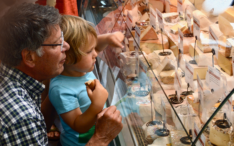 father and child looking at all the cheeses in the case at Mad River Taste Place