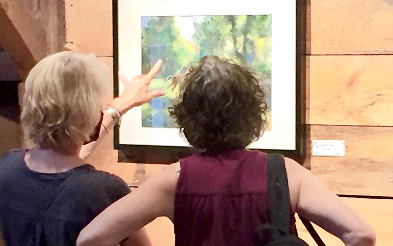 Two people viewing a piece from the Big Red barn Art Show. Photo: Roarke Sharlow