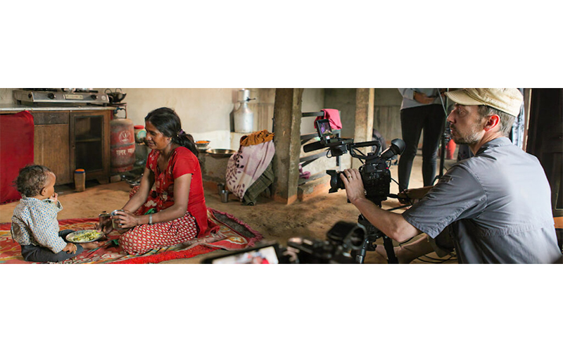 A mother can child eating a meal while being filmed.