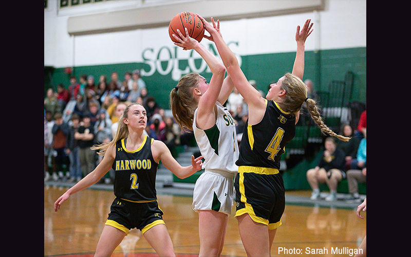 A Harwood player blocks a Montpelier player's shot in girls' high school basketball.