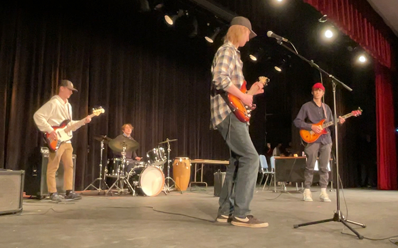 Nate Conyers, Emmet Lisai, Jonah Halter, and Gabe Frankel performing on the Harwood Auditorium stage.