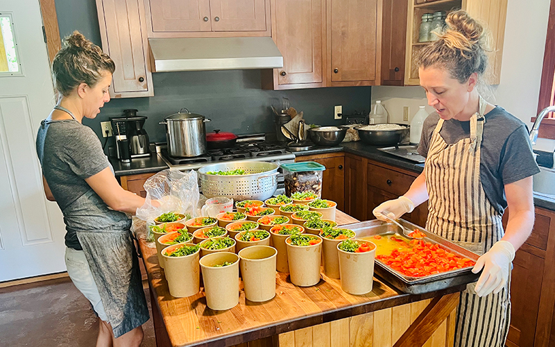 Lisa Mason, right in the striped apron, of Fiddleheads Cuisine in Moretown and Lulu Kalman of Slim Pickins Foods in Waitsfield, teamed up to create healthy to-go meals to support flood relief in Central Vermont. Photo courtesy Lisa Mason