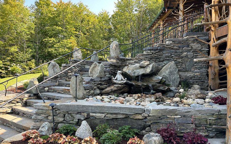 Ted LaRock and his crew spent two years creating these new stone steps at Moose Meadow Lodge in Duxbury. Weathered and aged wooden steps were replaced by this sweeping staircase that includes granite treads, an enormous granite landing, handcrafted steel railings that were installed on site, sentinel stones and a waterfall that sounds like a brook in the woods.  