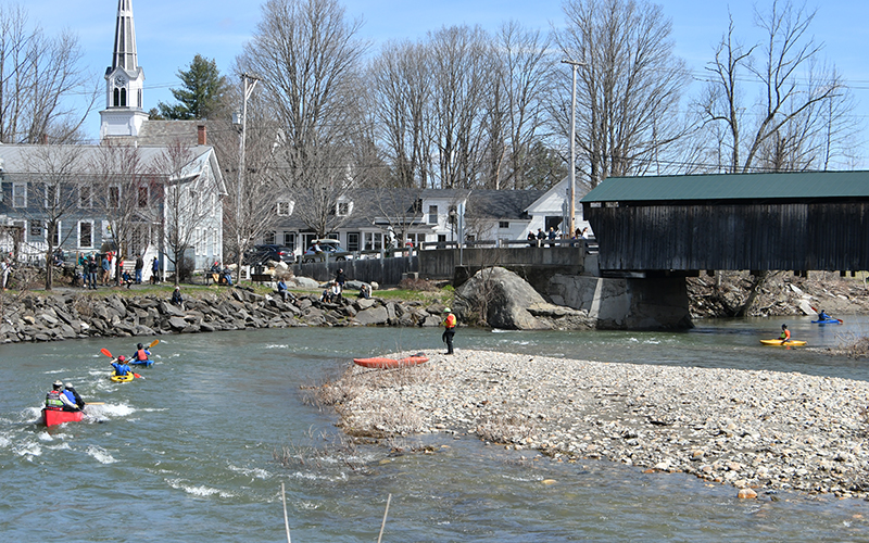 2024 Mad River Valley Triathlon helpers watch kayakers and canoers pass the Waitsfield Covered Bridge. Photo: John Williams