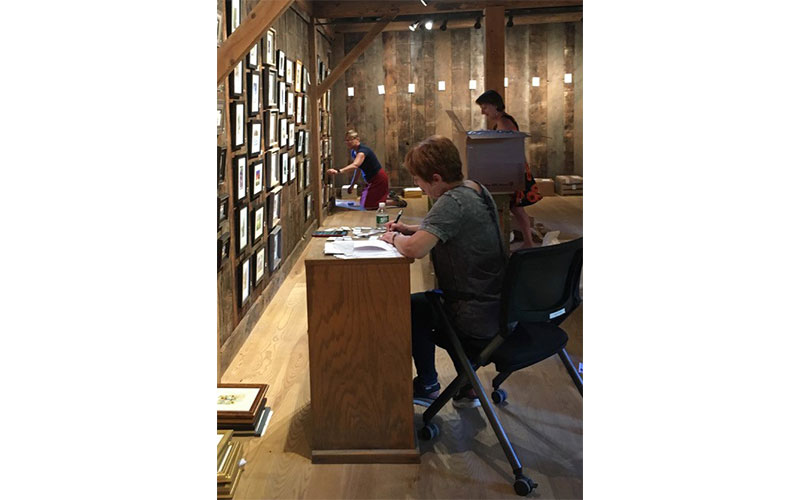 Photo: Gary Eckhart. Volunteers Nancy Mobley, Julie Burns and Dayna Lisaius hang paintings for the Green Mountain Watercolor Exhibition.